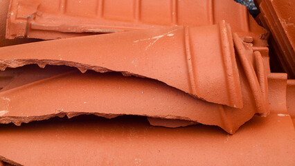 Broken red French roof tiles lie in a pile of rubble