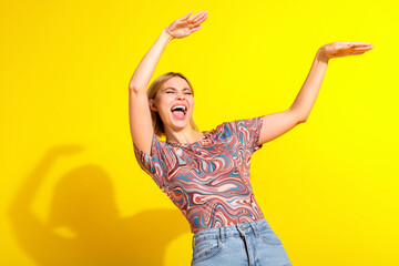 Happy young woman enjoying a cheerful moment on a vibrant yellow background dressed in trendy and...