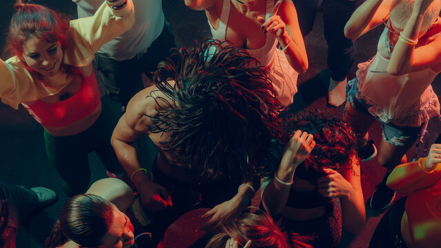 Top view of a lively party with people dancing energetically under colored lights. Concept of nightlife party, youth, summer, festivity, celebration