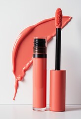 A coral liquid lipstick tube and applicator with a smooth wavy streak of coral lipstick on a white background