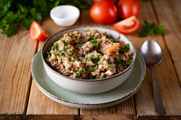 Buckwheat porridge with meat on a green plate for lunch on a wooden table. Buckwheat porridge with pork for dinner. Close-up.