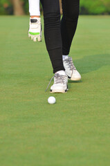 Crop image of a female golfer is about to pick the golf ball up on tee.