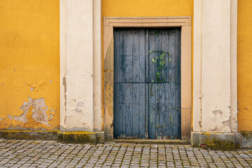Old weathered wooden door and flaking ochre wall in Czech Republic