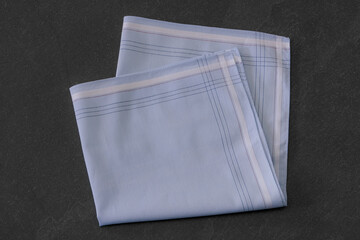 Folded blue handkerchief arranged on a dark background, showcasing classic men's accessories in a...