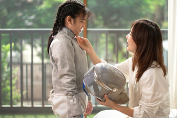 The mother of the girl fencer is taking care of her fencing gear. Caring for your growing child