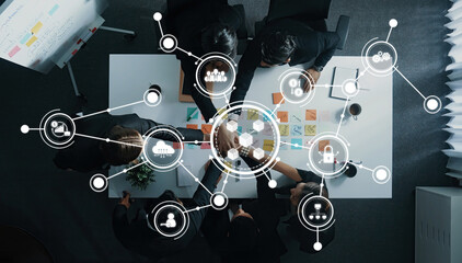 An overhead view of a collaborative business meeting showcasing teamwork and digital connections, with visual insights on the table in a bright white office setting. Amity