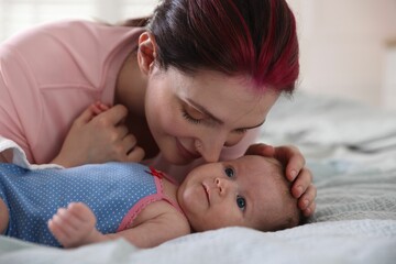 Mother putting her cute newborn baby to sleep on bed at home, closeup