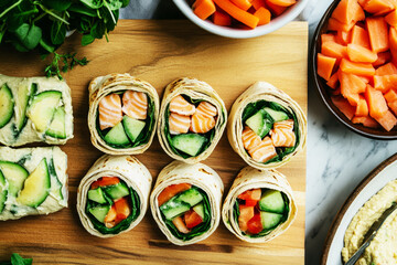 Fresh sushi rolls filled with salmon and greens are arranged gracefully on a wooden board alongside smoked salmon, avocado, and colorful veggies. Perfect for a nutritious breakfast