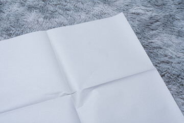 Minimalistic newspaper mockup with blank folded paper lying on a fluffy gray carpet. Layout for...