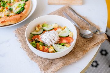 
Fresh vibrant salad with crisp vegetables, croutons, and creamy dressing, accompanied by pizza and...