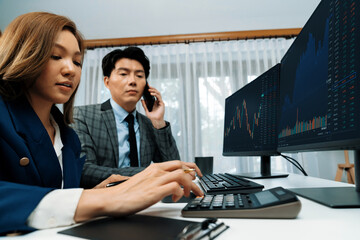 Smiling Asian businessman calling to broker dynamic stock exchange database with woman business...