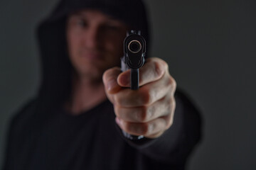Armed Man Threatening with Gun in Focus Pointing Weapon Toward Camera
