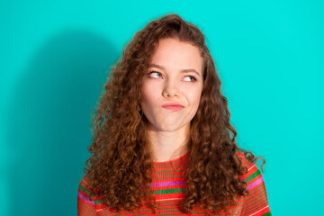 Cheerful young woman in a stylish striped outfit posing playfully against a turquoise background