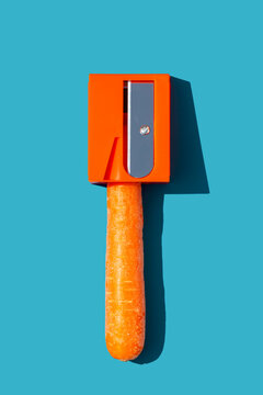 Top view of carrot in pencil sharpener on blue background