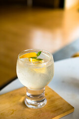 A refreshing citrus sparkling drink with orange slices and mint, chilled in a stylish glass on a wooden coaster. Ideal for summer, cocktails, or beverage themes