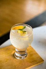 A refreshing citrus sparkling drink with orange slices and mint, chilled in a stylish glass on a wooden coaster. Ideal for summer, cocktails, or beverage themes