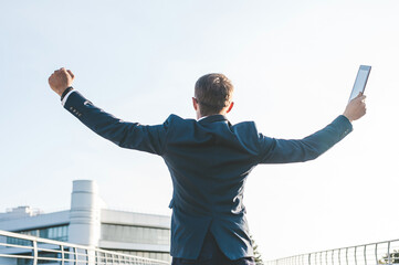 Victorious Businessman with Raised Arms and Tablet Achievement and Success
