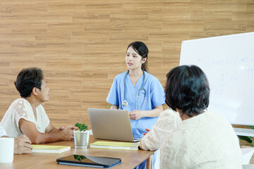 Professional Southeast Asian nurse consulting elderly patients in bright modern care facility,...