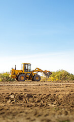 Yellow bulldozer at a construction site. Big wheel excavator leveling and clearing the land plot...