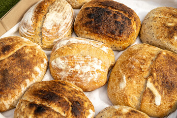 Artisan sourdough homemade craft bread on white textile background. Natural light with soft shadows, close-up top view.