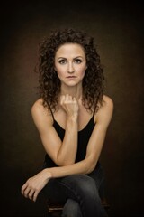 Fototapeta premium A woman sitting on a stool with her hand on her chin