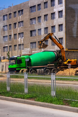 A large green concrete mixer truck is being loaded with fresh concrete