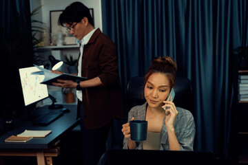 Businesswoman calling with customers with drinking coffee to make new project job at modern office while coworker checking paperwork business plan database report meeting at over late night. Infobahn.