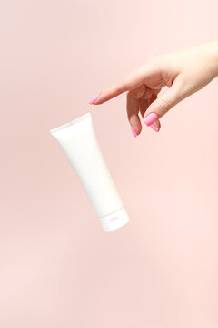 Woman's hand with pink nails on soft pink background