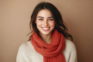 A smiling woman with long brown hair wearing a terracotta knitted scarf against a neutral background.