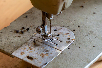 presser foot and needle plate of an old, dusty sewing machine. Visible rust, stains, and wear...