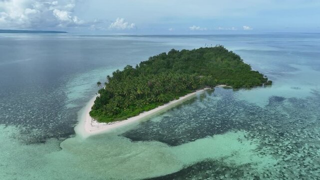 A remote, tropical island is surrounded by sand, seagrass, and coral reef in Wakatobi National Park, Indonesia. This beautiful area is a popular destination for divers and snorkelers.