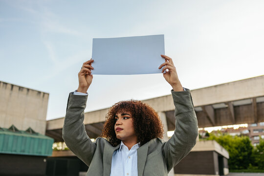 Trans woman holding blank sign in urban setting outdoors