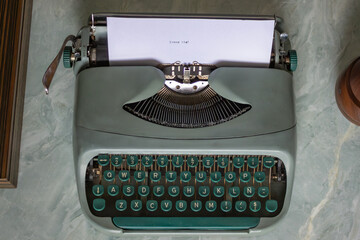 Vintage typewriter sits on a marble table, displaying the typed words dream big, evoking a sense of nostalgia, inspiration, and the pursuit of creative endeavors