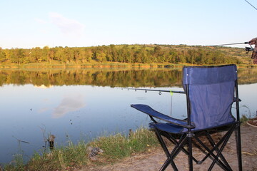 Peaceful lakeside scene with a fishing chair and rod.