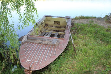 Old wooden boat rests by a tranquil lakeside.