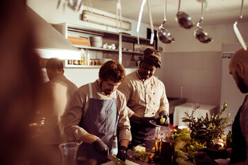 Professional chefs preparing food together in a busy restaurant kitchen