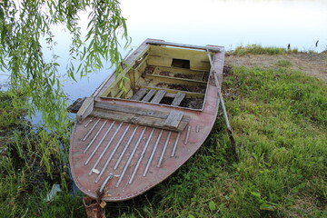 Weathered wooden boat on grassy lakeside.