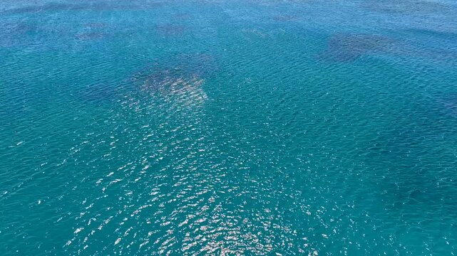 Aerial view of the Mediterranean Sea. Blue waves and water surface texture. Summer sea waves natural background. Aerial view of clear sea water texture. Sun glare in turquoise water.