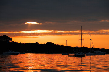Sunset over Studland Bay, with the silhouette of anchored boats: Isle of Purbeck, Dorset, UK