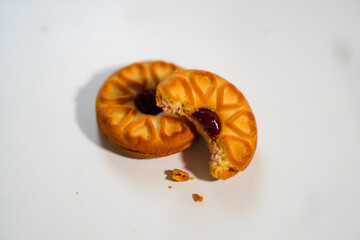 Two biscuits with grape jam and one half eaten, white background. top view photo