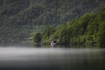 fishing in the lake Tranquil lakeside scene featuring a small wooden cabin surrounded by dense...