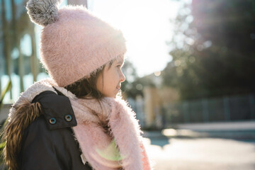 Pensive girl child wearing winter clothes standing outdoors during a cold day - Concept of childhood concerned about environmental conservation and the planet earth