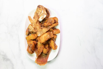 A delicious platter featuring crispy fried fish served with golden brown plantains, perfect for a...