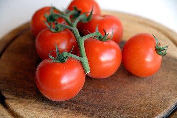 Some fresh vine ripened tomatoes on a wooden choppong board.