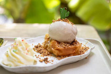 Delicious dessert featuring creamy ice cream on a flaky pastry, garnished with crumbles and mint. Perfect for food lovers.
