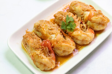 Delicious golden-brown fried prawns served on a white plate, garnished with cilantro, perfect for seafood lovers.