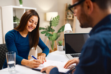 Young woman signing contract with financial advisor at home office