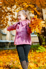 Little girl holding yellow autumn leaves, smiling outdoor park. Seasonal joy child happiness concept