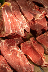 Raw prime steaks. Variety of fresh black angus prime meat steaks T-bone, New York, Ribeye, Striploin, Tomahawk cutting board on black or dark background. Set of various classic steaks. Top view.