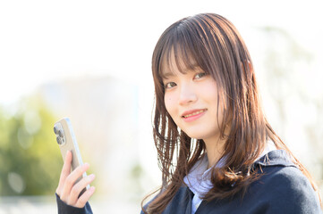 スマホを持って微笑む日本人女子高生